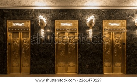 16x9 crop of elevators in vintage art deco building with marble walls, golden sconces and detailed doors Royalty-Free Stock Photo #2261473129