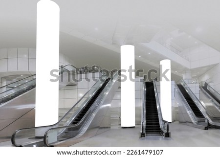 mock up out of home OOH; wide angle view of generic empty train station with escalators for advertising mockup display. Tall blank white pillars for easy poster placements