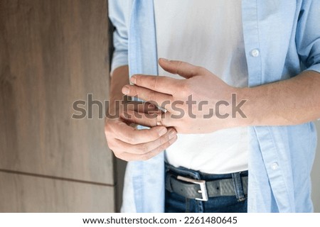 A man removes a gold wedding ring from his left hand ring finger Royalty-Free Stock Photo #2261480645