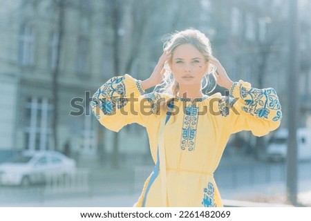 A young girl stands in a Ukrainian national ethnic embroidered dress on a sunny day.