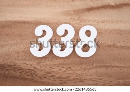White number 338 on a brown and light brown wooden background.