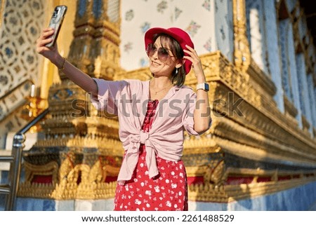 happy thai woman taking seflie at wat arun temple in bangkok thailand outside during the day