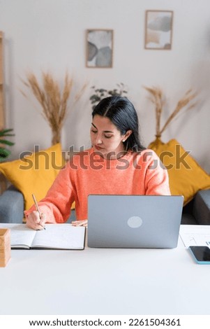 woman writing in notepad working from home