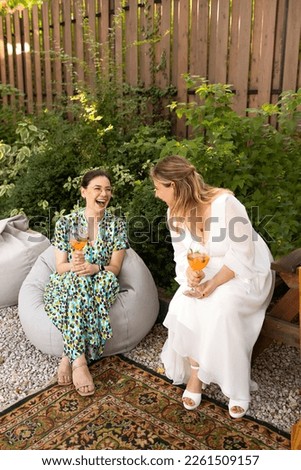 Happy female friends spending time together, young woman drinking Aperol spritz cocktail on outdoors wedding party. Happiness and celebration concpt