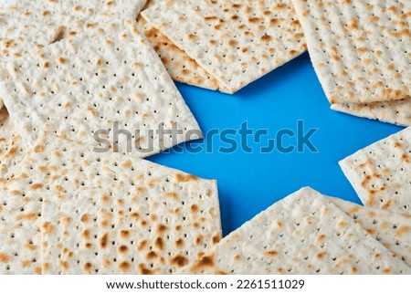 Passover celebration concept. Blue Star of David made from matzah, white and yellow roses, kippah and walnut on bluebackground. Traditional ritual Jewish Passover food. Pesach Jewish holiday. Mock up Royalty-Free Stock Photo #2261511029