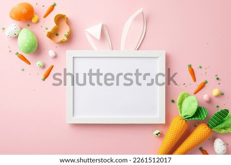 Easter decor concept. Top view photo of photo frame with easter bunny ears colorful eggs carrots baking mold and sprinkles on isolated pastel pink background with blank space