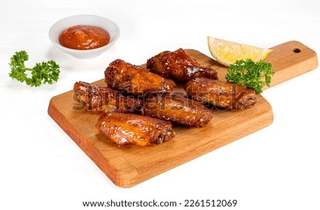 Grilled chicken wings with ketchup and sauces on a wooden board. Traditional baked bbq Royalty-Free Stock Photo #2261512069