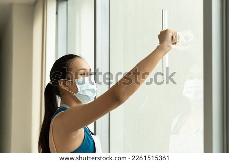 Professional asian immigrant worker woman cleaning windows glass, hard working and diligent domestic helper working on housework Royalty-Free Stock Photo #2261515361
