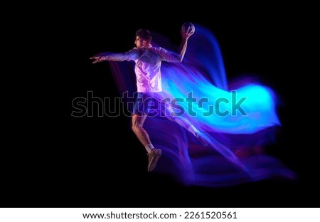Side view. Winning goal. Young man, professional handball player in motion, playing over black background with mixed lights effect. Concept of sport, action, motion, championship, sportive lifestyle