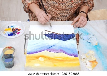 Woman artist paints a picturesque picture. Master class in fine arts.