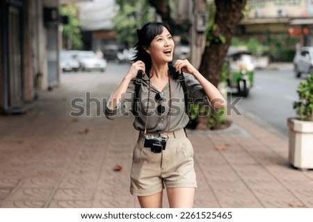 Young Asian woman backpack traveler enjoying street cultural local place and smile. Journey trip lifestyle, world travel explorer or Asia summer tourism concept. Traveler checking out side streets.
