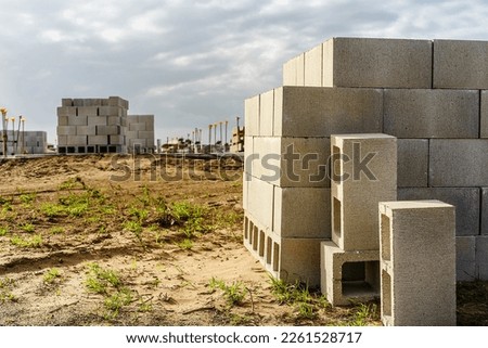 Stack of concrete blocks (foreground focus) on sandy lot for construction of a single-family house in a suburban residential development in southwest Florida Royalty-Free Stock Photo #2261528717