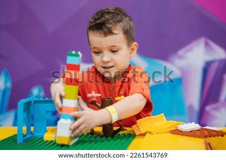 Educational toys. A picture of a boy's child playing with colorful plastic bricks at a table. The kid has fun and builds from bright constructor cubes. Early learning.