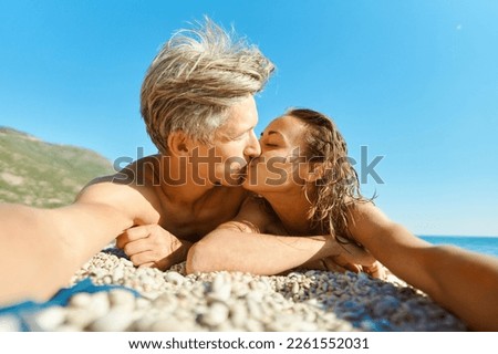Portrait of couple in love kissing on sunny beach and making selfie picture on romantic honeymoon holiday or vacation travel