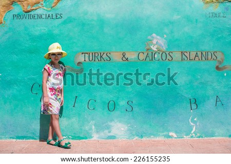 Little girl near big map of Caribbean island Turks and Caicos painted on the wall