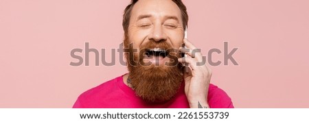 laughing bearded man with closed eyes talking on smartphone isolated on pink, banner