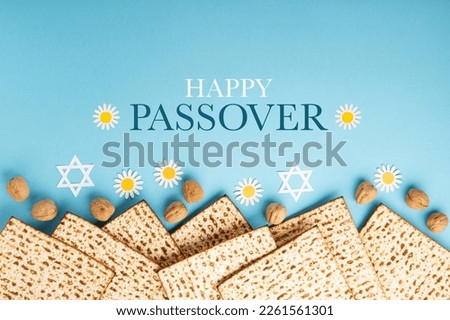 Jewish holiday Passover greeting card concept with matzah, nuts and tulip flowers on blue table. Seder Pesach spring holiday background, top view, copy space. Royalty-Free Stock Photo #2261561301