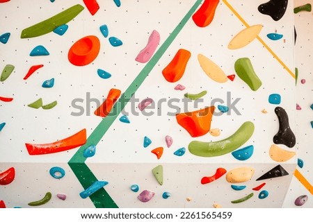 Wall with climbing holds in gym. Practicing rock-climbing on a rock wall outdoor. Xtreme sports and bouldering concept.  rock climber climbs on a rocky wall.