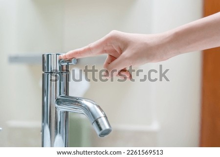 Save water. Volunteer keeps turning off the running water in the bathroom to protect environment. Greening planet, reduce global warming, Save world, life, future, risk energy, crisis , water day. Royalty-Free Stock Photo #2261569513