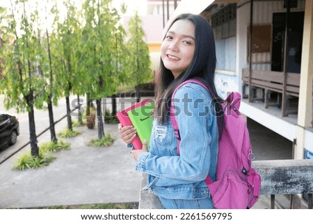 Shool girl hold book with backpak standing at campus.
