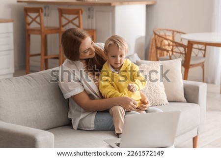 Mother with her little son watching cartoons at home