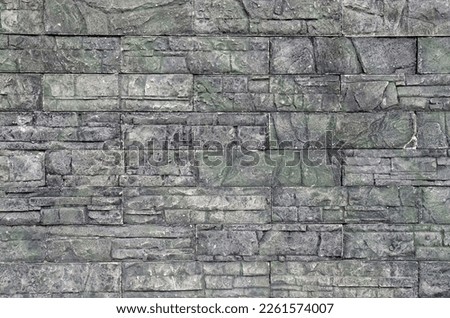 Gray and green cladding tiles imitating stone wall closeup

