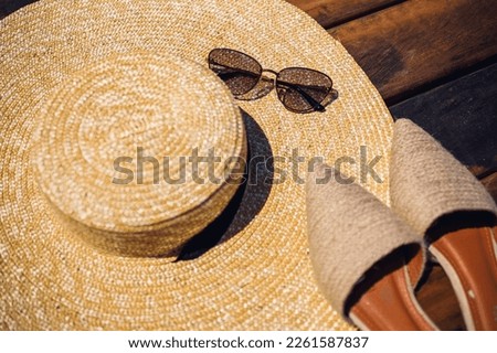 Women summer hat, sunglasses and mules shoes lie on a wooden background. Place for an inscription or advertisement Royalty-Free Stock Photo #2261587837