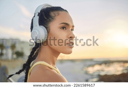 Headphones, exercise music and woman at beach thinking about training, exercising or workout. Sports, fitness and female athlete streaming radio, podcast or audio after running at sunset by ocean. Royalty-Free Stock Photo #2261589617