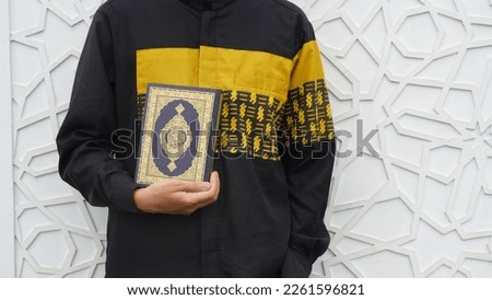 Man Holding and reading quran. Islamic Background. Arabic on the cover translated with Quran. pegang quran. muslim. muslimah
