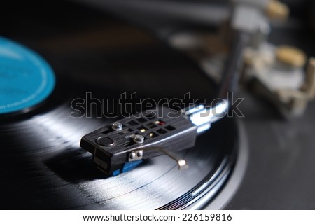 Picture of a vinyl record playing. Blue label and needle