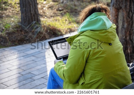 young woman with laptop on garden plot, landscaping designer, rear view, selective focus