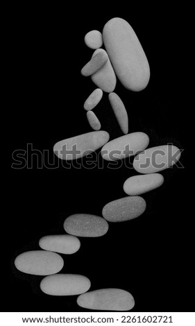 one Hiker man climbing with big heavy backpack on mountain. isolated on black background. male sign, symbol made from many white pebbles, stones. peak of mountain.