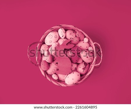 Easter composition on a monochrome background, Viva Magenta color of the year.  Wicker basket with Easter eggs and a rabbit.  Concept style, toning, flat lay top view.