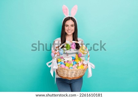 Photo of glad lady hold easter basket prepare go church wear rabbit ears striped sweater isolated blue color background