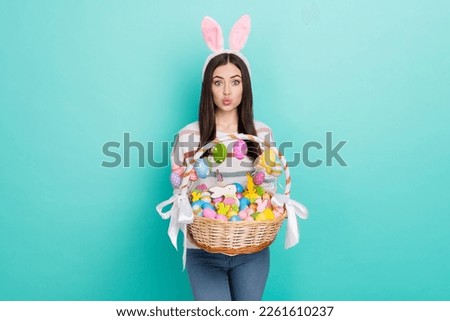 Photo of excited flirty lady dressed striped pullover hare headband holding colorful easter basket isolated teal color background