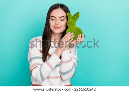 Photo of sweet dreamy woman wear striped sweater holding green bunny closed eyes isolated turquoise color background