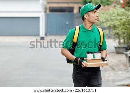 Courier in green uniform delivering lunch to customer