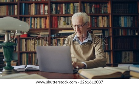 Senior man scientist typing on laptop, working on research at library, enjoying his day