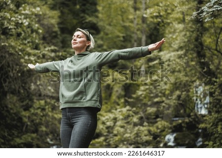 Woman with arms outstretched taking deep breath at nature and enjoying in fresh air in the mountain. Royalty-Free Stock Photo #2261646317