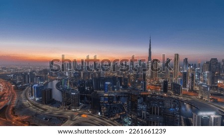 Panoramic skyline with modern architecture of Dubai business bay and downtown towers day to night transition timelapse. Aerial view with canal and construction site after sunset Royalty-Free Stock Photo #2261661239