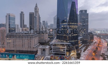 Dubai International Financial district night to day transition timelapse. Aerial view of business office towers before sunrise. Illuminated skyscrapers with hotels near downtown