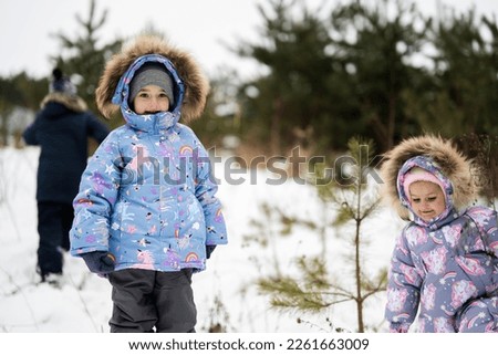 Three kids walking in winter forest.