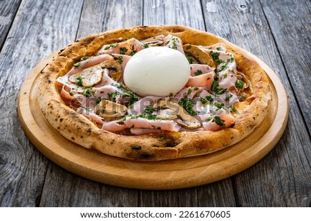 Circle prosciutto burrata pizza with mushrooms on wooden table 