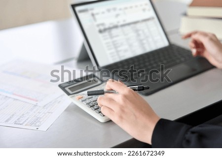 Asian woman using accounting software and calculator Royalty-Free Stock Photo #2261672349