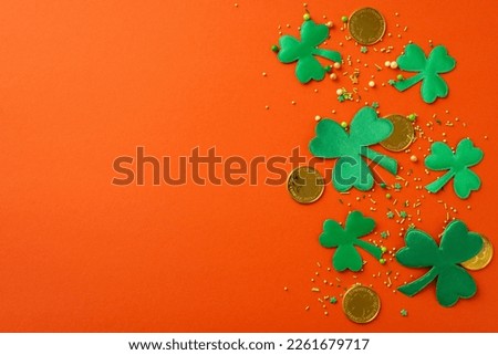Saint Patrick's Day concept. Top view photo of trefoils gold coins and sprinkles on isolated bright orange background with blank space