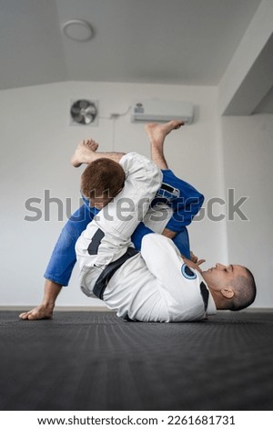 Brazilian jiu jitsu bjj training or sparing two athletes fighters dill martial arts technique at gym on the tatami mats wear kimono gi black belt instructor demonstrate submission armbar juji gatame Royalty-Free Stock Photo #2261681731