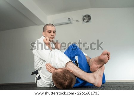 Brazilian jiu jitsu bjj training or sparing two athletes fighters dill martial arts technique at gym on the tatami mats wear kimono gi black belt instructor demonstrate submission armbar juji gatame Royalty-Free Stock Photo #2261681735