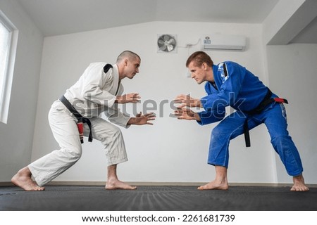 Brazilian jiu jitsu bjj training or sparing two athletes fighters dill martial arts technique at gym on the tatami mats wear kimono gi black belt instructor demonstrate technique stand up Royalty-Free Stock Photo #2261681739