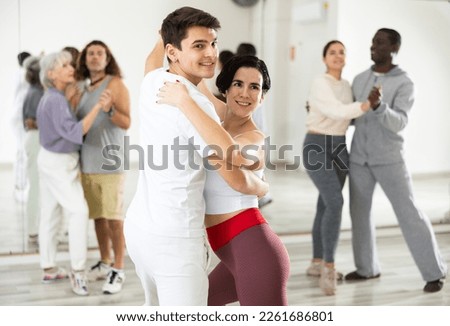 Young smiling guy learning to dance waltz paired with expressive positive Hispanic girl in dancing class Royalty-Free Stock Photo #2261686801