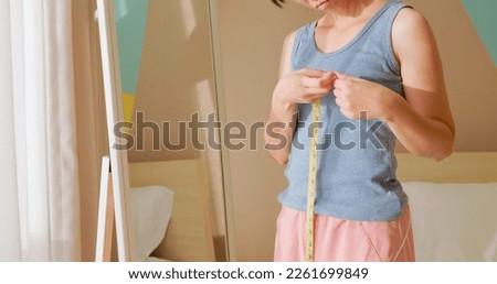 asian unhappy woman is dissatisfied while she measuring her chest and breast in front of mirror Royalty-Free Stock Photo #2261699849